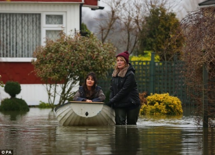 Christine Baker, right, helps Sue Hyland through the flood waters at Abbey Fields caravan park in Chertsey, Surrey following floods last week Christine Baker, right, helps Sue Hyland through the flood waters at Abbey Fields caravan park in Chertsey, Surrey following floods last week