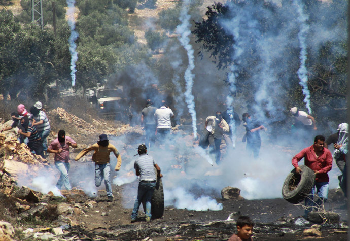Palestinian protesters run away from tear gas fired by Israeli soldiers during clashes following a protest against the Jewish settlement of Qadomem, in the West Bank village of Kofr Qadom near Nablus May 23, 2014.