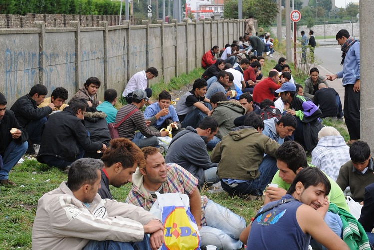 Immigrants eating food by railway sidings in Calais Immigrants eating food by railway sidings in Calais