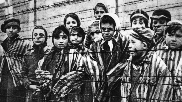 Children behind a barbed wire fence at the Nazi concentration camp at Auschwitz in southern Poland. (Photo by Keystone/Getty Images)