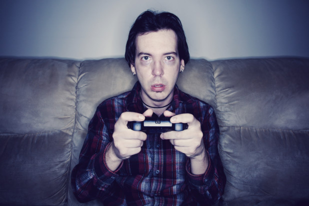Man sitting on a couch playing video games in a dark room
